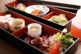 ローストビーフや煮物が並んでいる御膳の写真