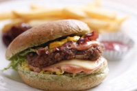 ポテトやケチャップが背後にあるハンバーガーの写真