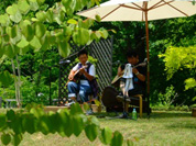 森林の広場に置かれた椅子でくつろぐ人の写真