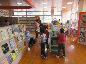 図書室で本棚や本を見ている子供たちの写真