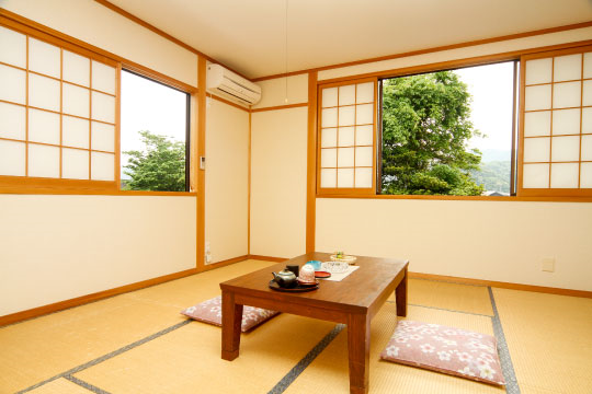 開けられた障子から外の木が見える和室の写真