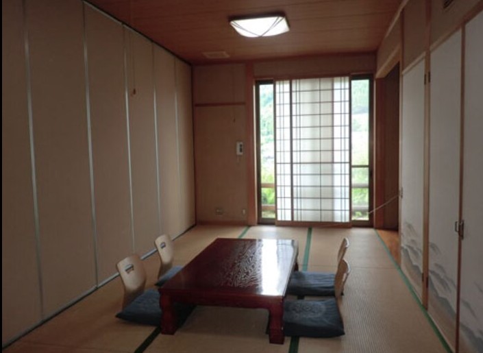 紺色の座布団とテーブルが置かれた和室の写真