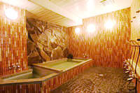 茶色の壁をした浴室に薄緑色のお湯が入っている写真