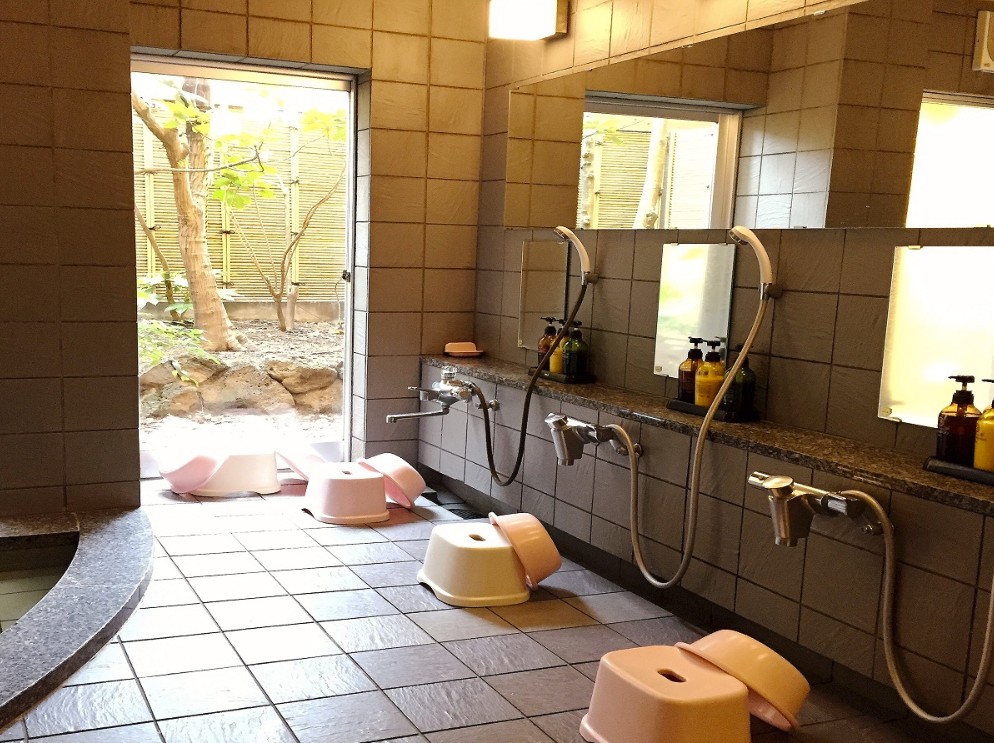 風呂桶やシャワー台が並んでいる銭湯の写真