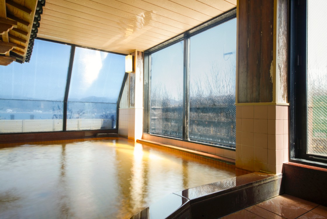 ガラスの向こうに遠景が見える温泉の写真