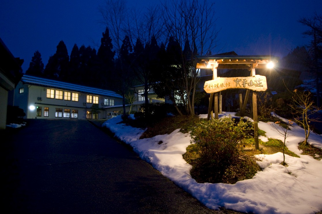 雪が積もった芝生に設置されている看板がライトアップされている写真