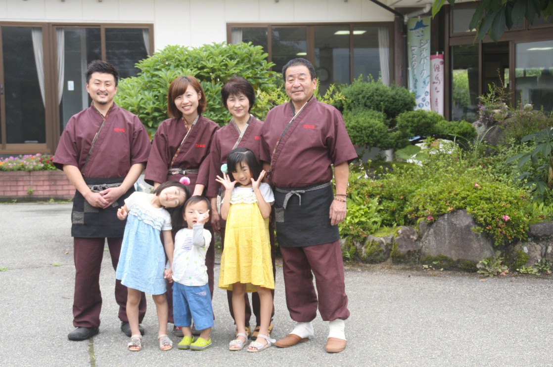 小豆色の服を着た人たちと子供が並んでいる写真