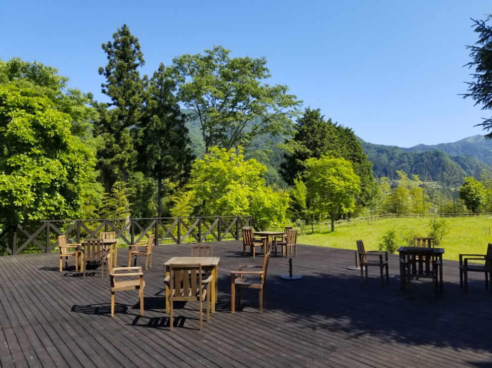 ウッドデッキに複数のテーブルや椅子が並べられている写真
