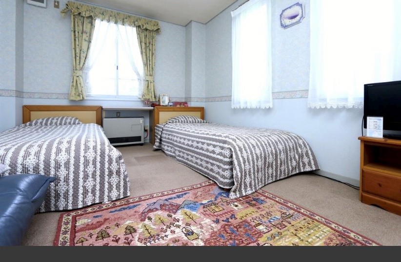 絨毯が敷かれてベッドが2つ並んでいる写真