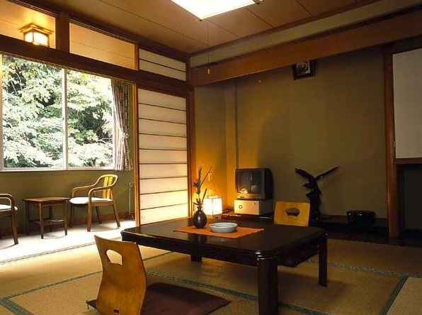 雪の積もった木が窓から見える和室の写真