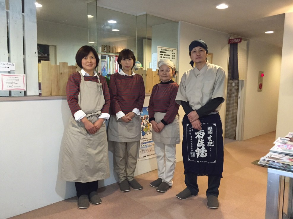 エプロンを付けた人や鉢巻を付けた人たちが並んでいる写真