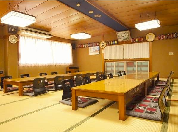 テーブルと座布団が置かれた広い和室の写真