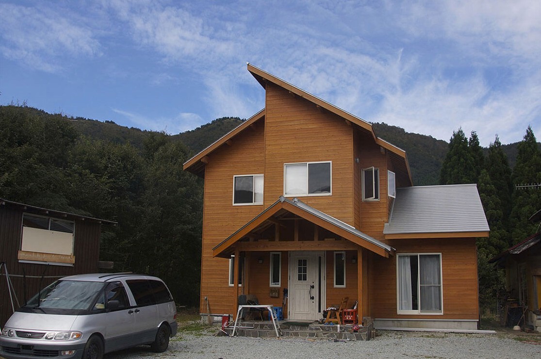 三角屋根をした茶色の建物の側に車が停まっている写真