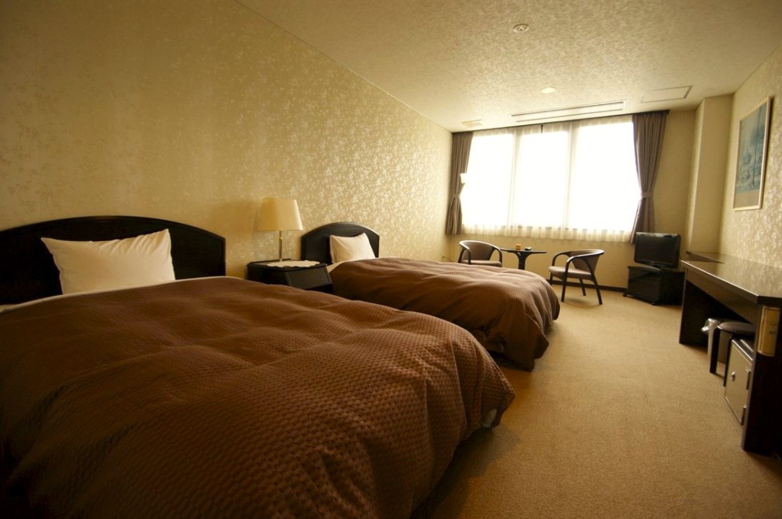 茶色の布団がかかったベッドが2つ置かれている部屋の写真