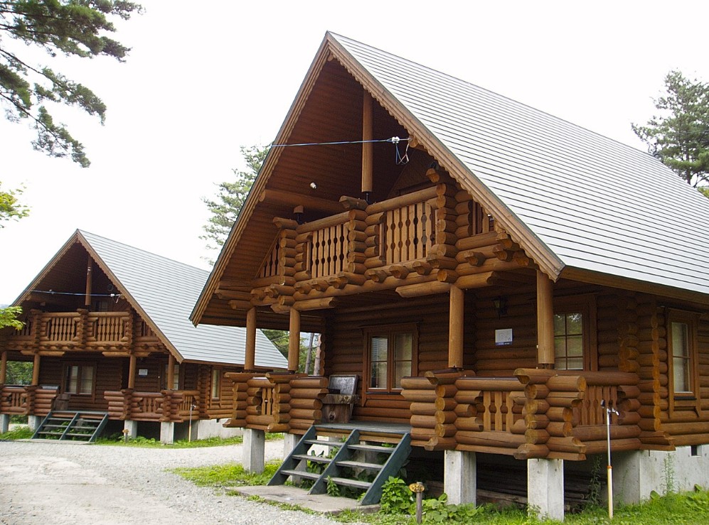 白い三角屋根をしたログハウスが2棟並んでいる写真