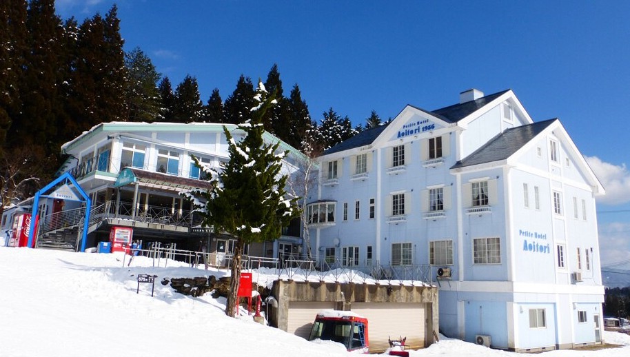 辺りに雪が積もった白い建物の写真