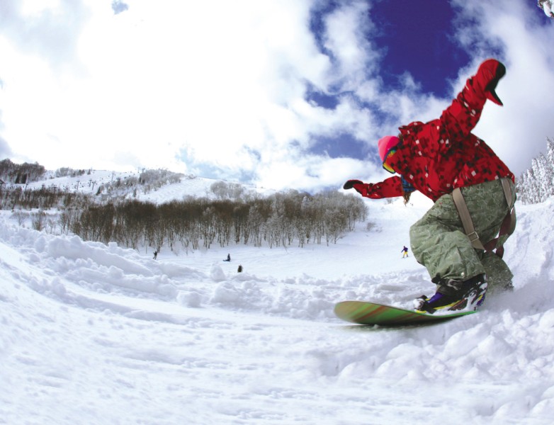赤いジャケットを着た人がスノボーをしている写真