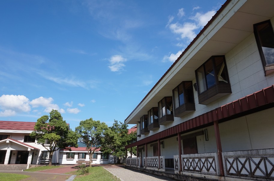 赤色の屋根をした2階建てで横長の建物と庭の写真