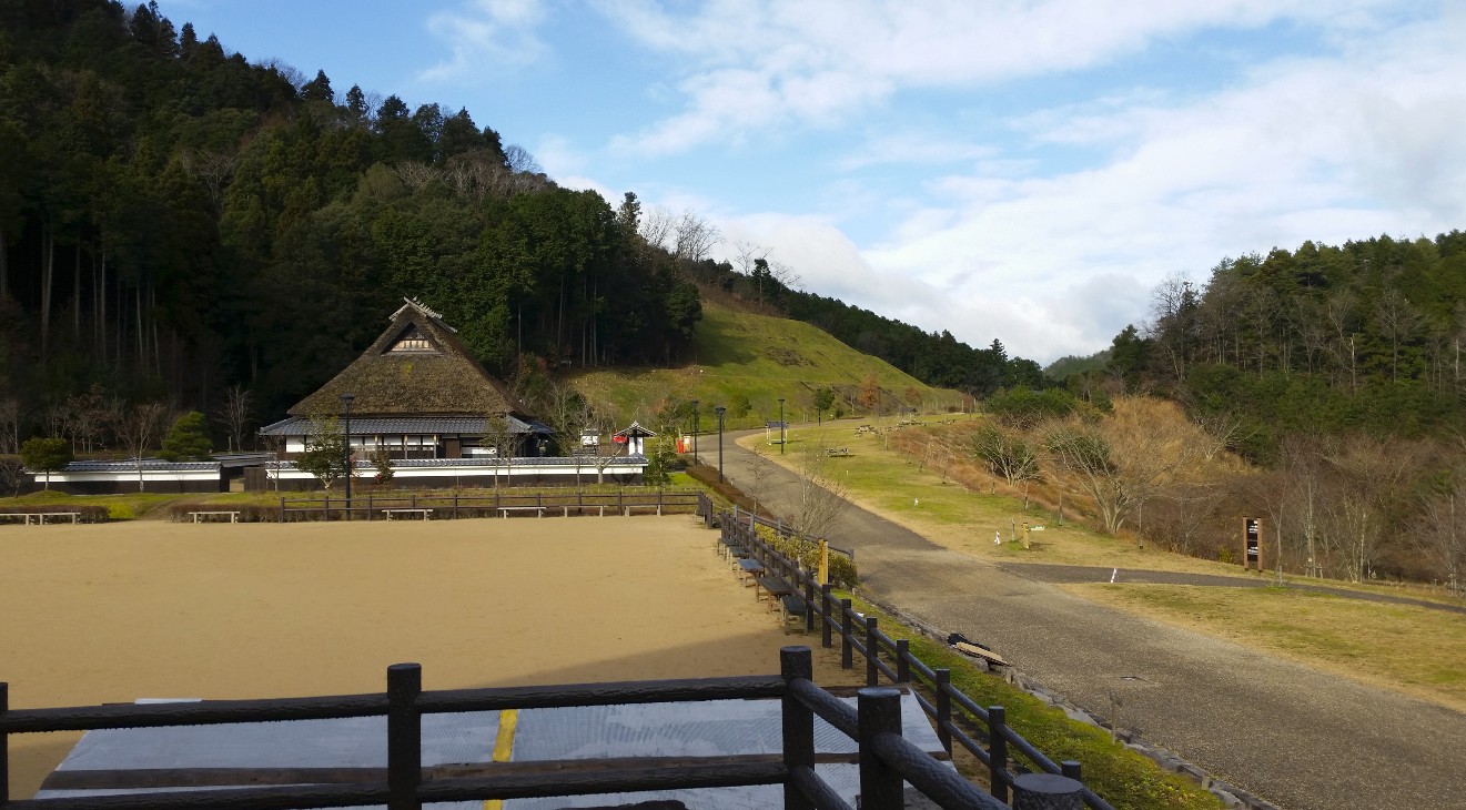 道のわきにかやぶき屋根の家屋が建っている写真