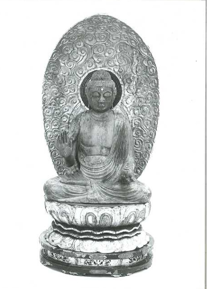 大きな光背を背負い、台座に座り右手を胸前に上げたポーズの如来像の白黒写真