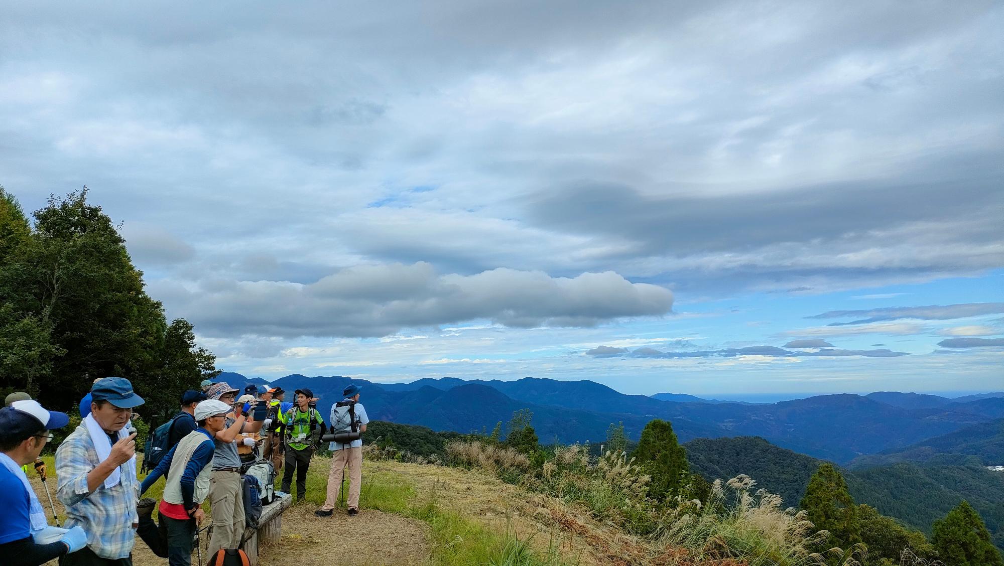 眺めのいいところで景色を見ている登山客の写真
