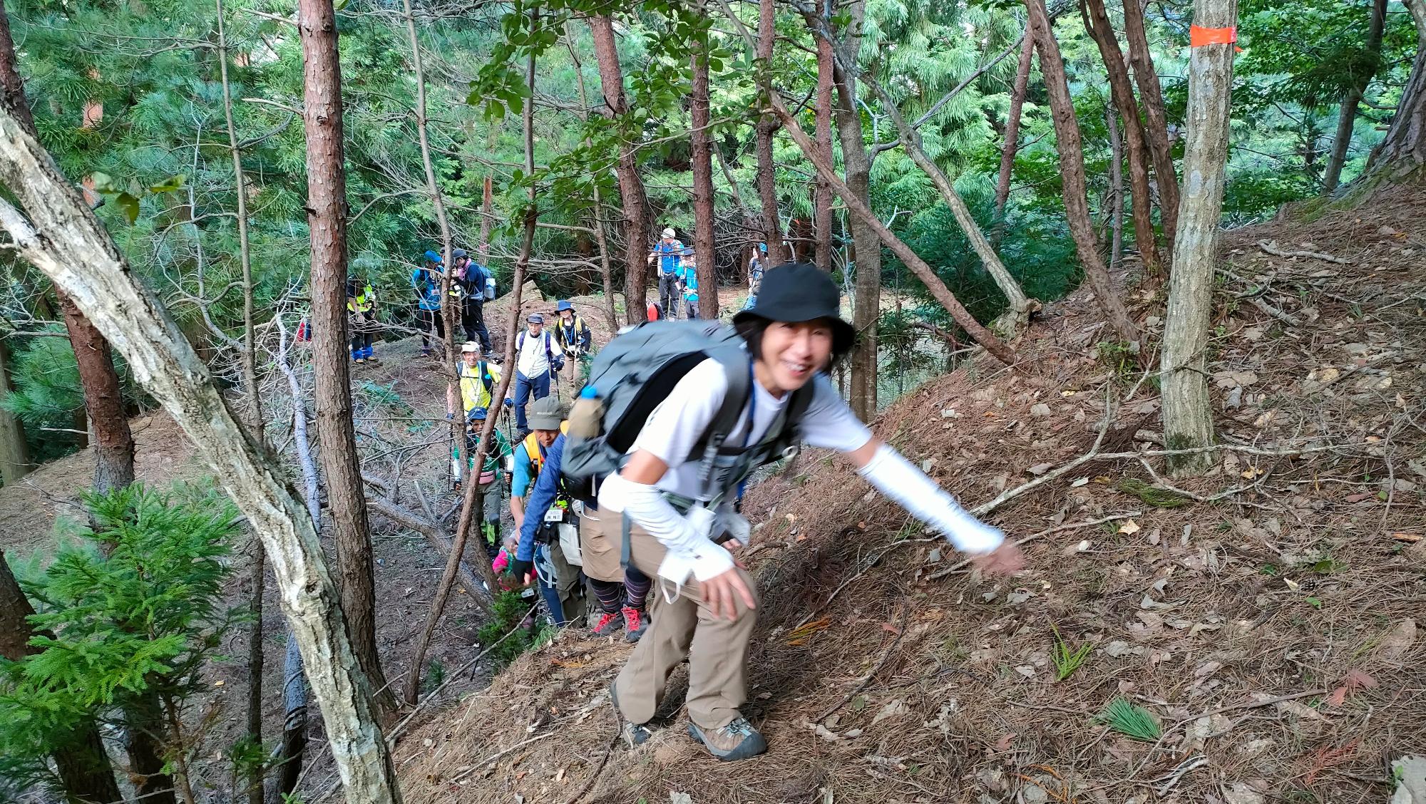 急な斜面を登っている女性がこちらに笑顔を見せている写真