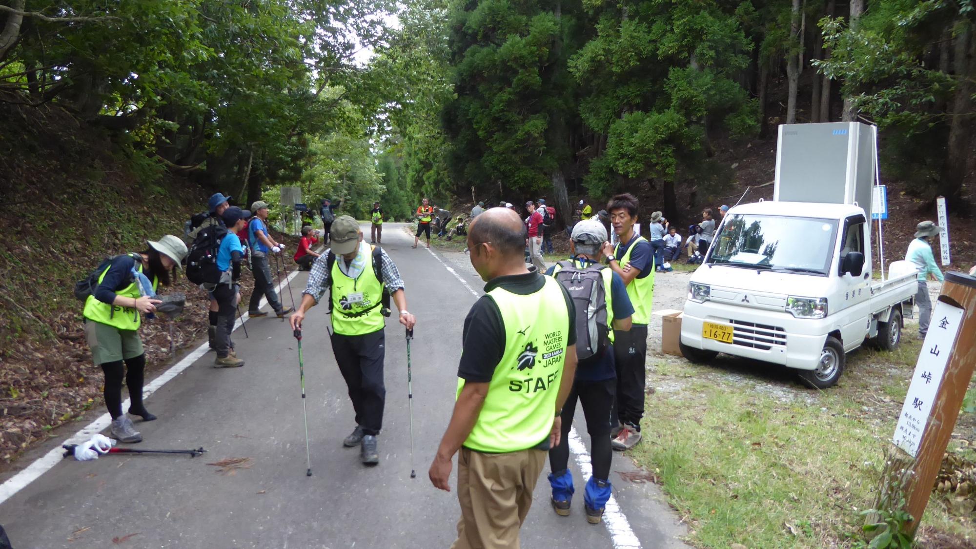 ゼッケンを着た人たちが道路に集まっている写真