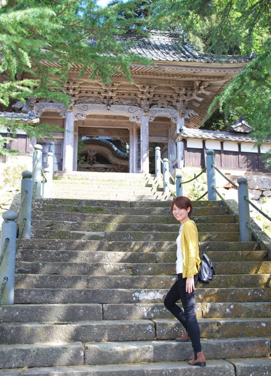 山門前の階段でこちらへ振り向く女性の写真