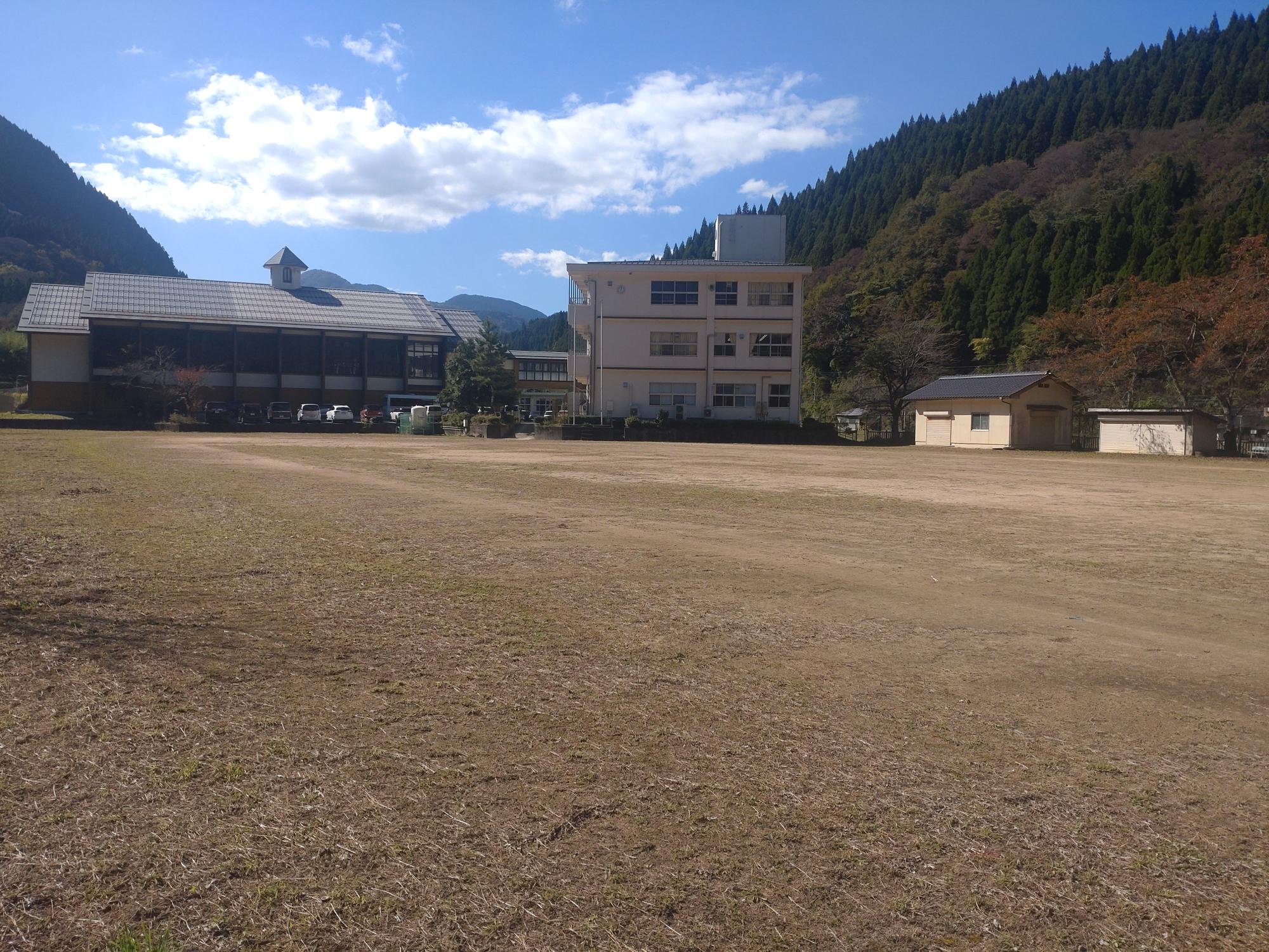 建物の前に広がる土のグラウンドの写真