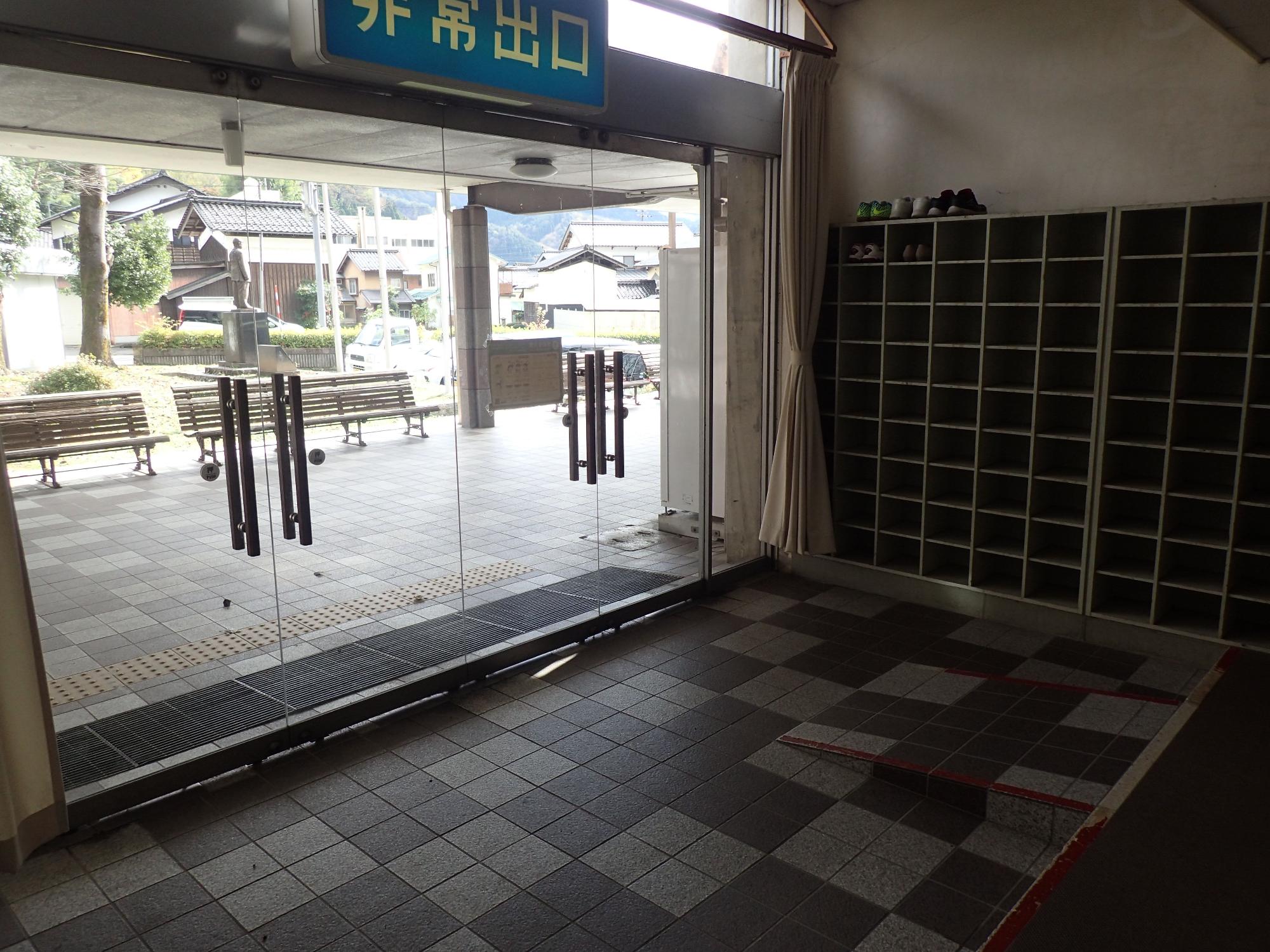 2つの両開きのガラス扉の傍に靴箱棚がある玄関の写真