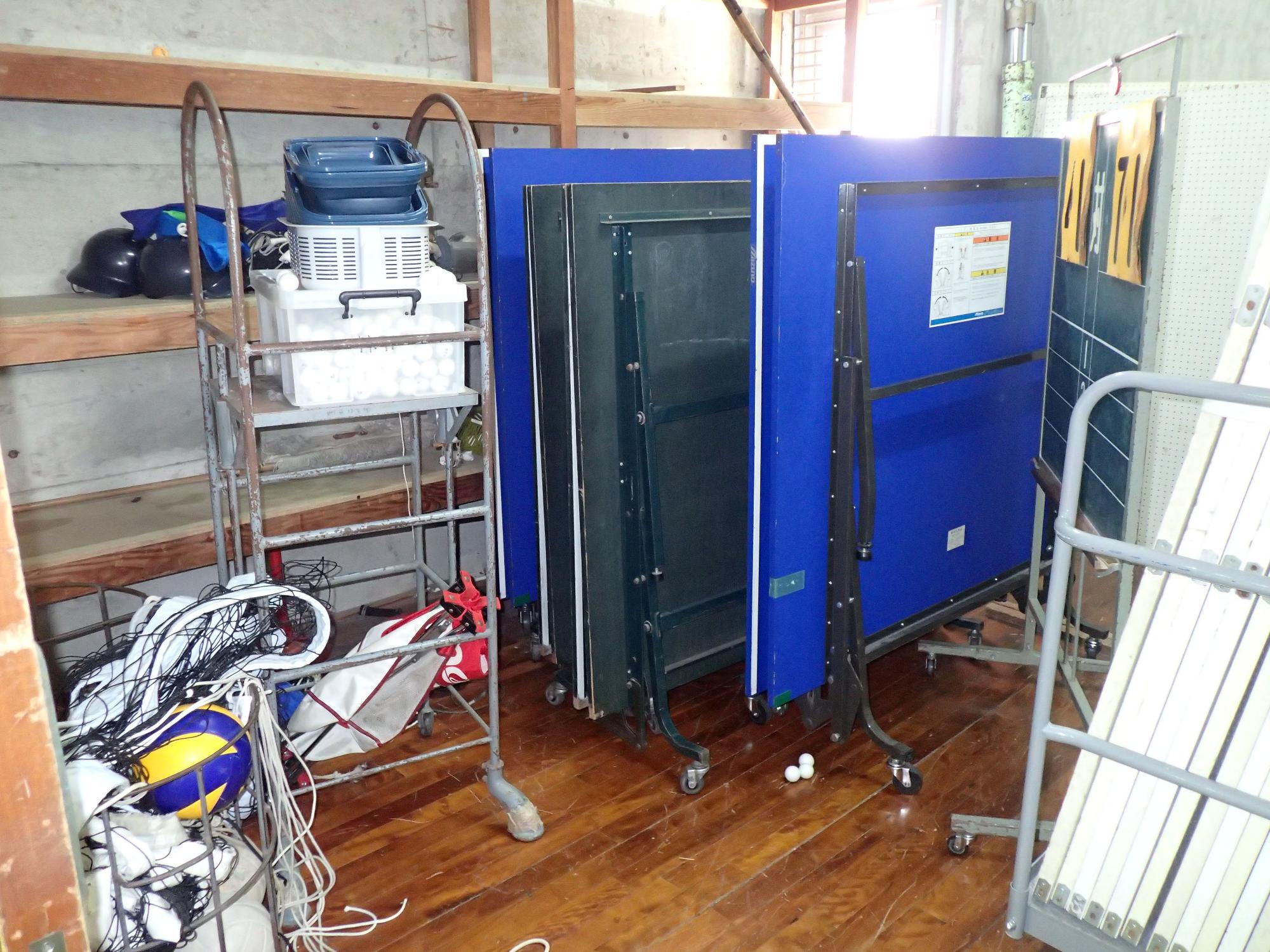 ボールや畳んだ台、ネットなどが棚の傍におかれた部屋の写真