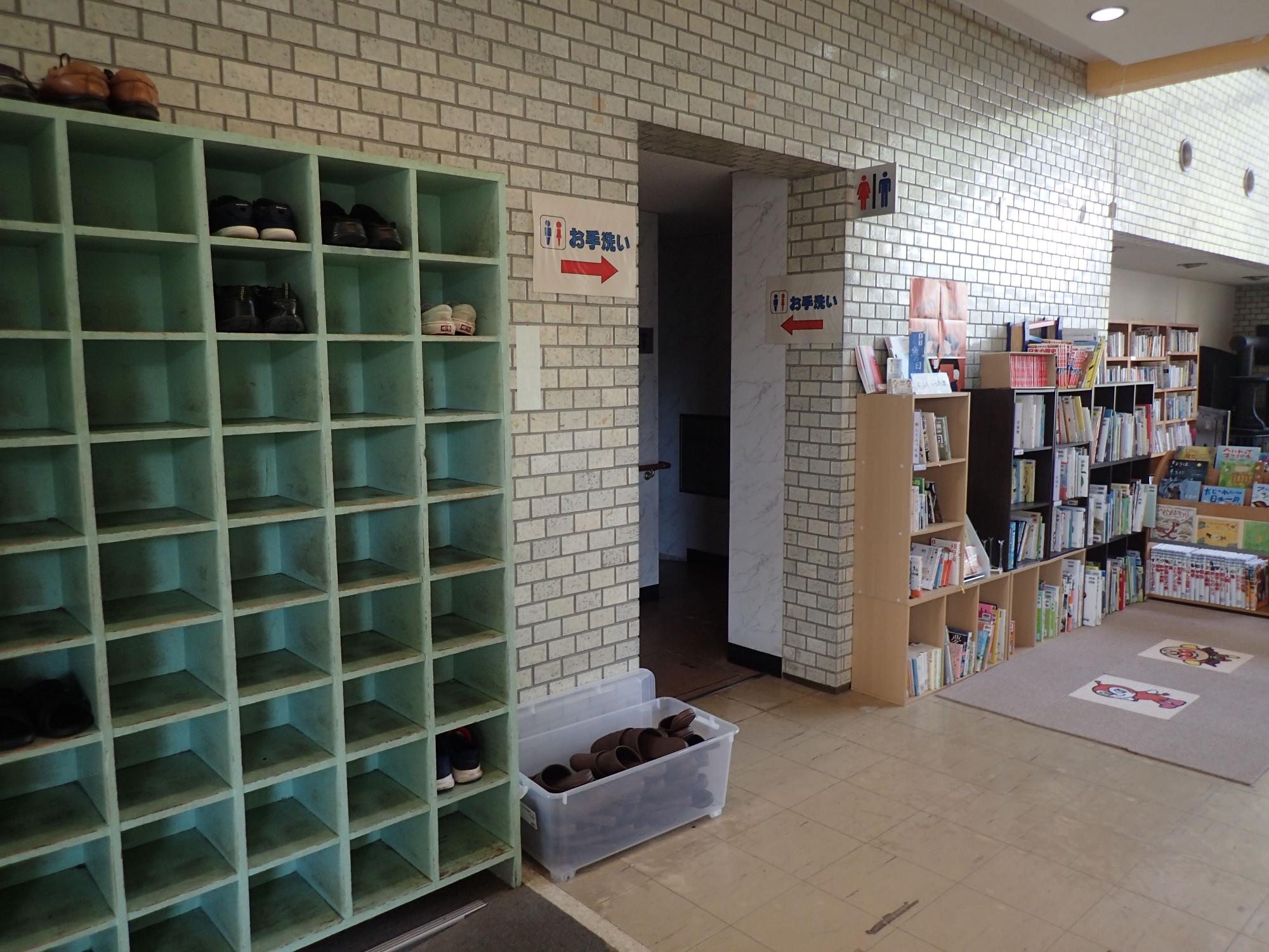 傍に靴箱棚が置かれたトイレの入り口写真