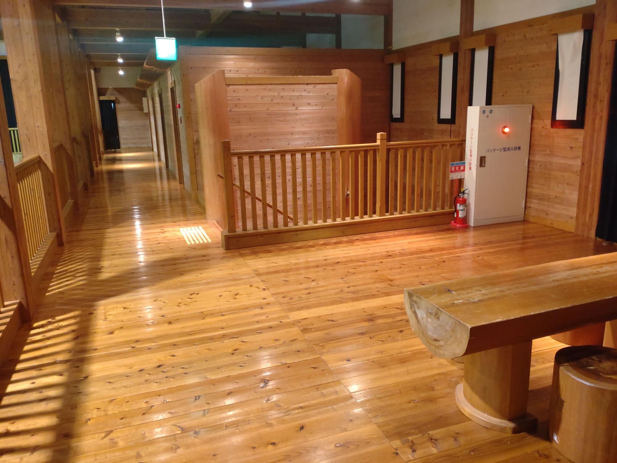 奥まで続く廊下と木製のベンチが設置された室内の写真