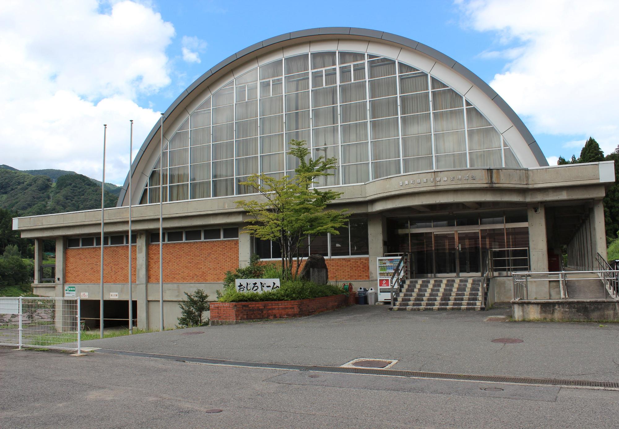 「おじろドーム」と書かれた館銘板のあるアーチ状の建物の外観の写真