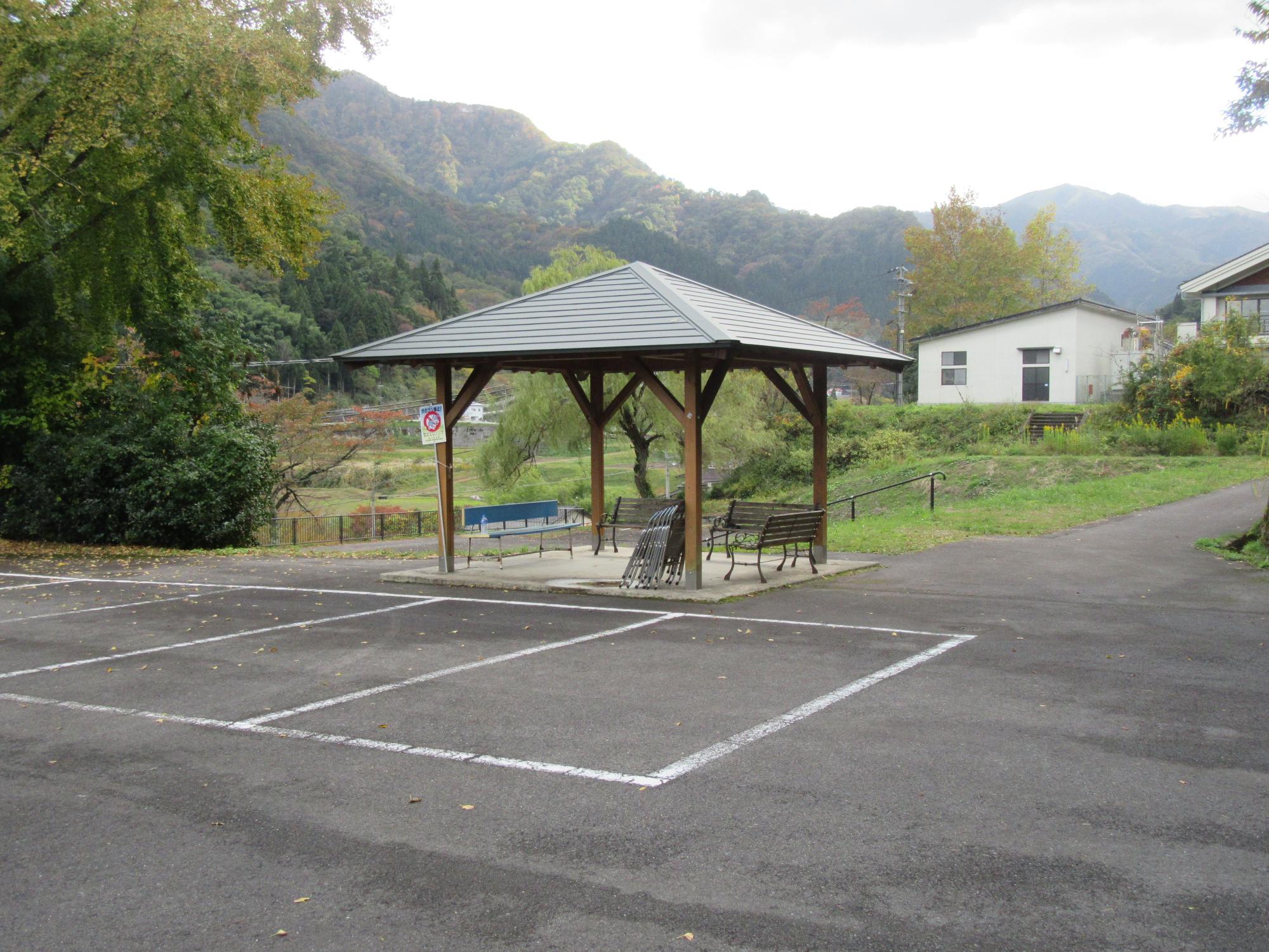 アスファルトの駐車場の奥に設置された東屋の写真