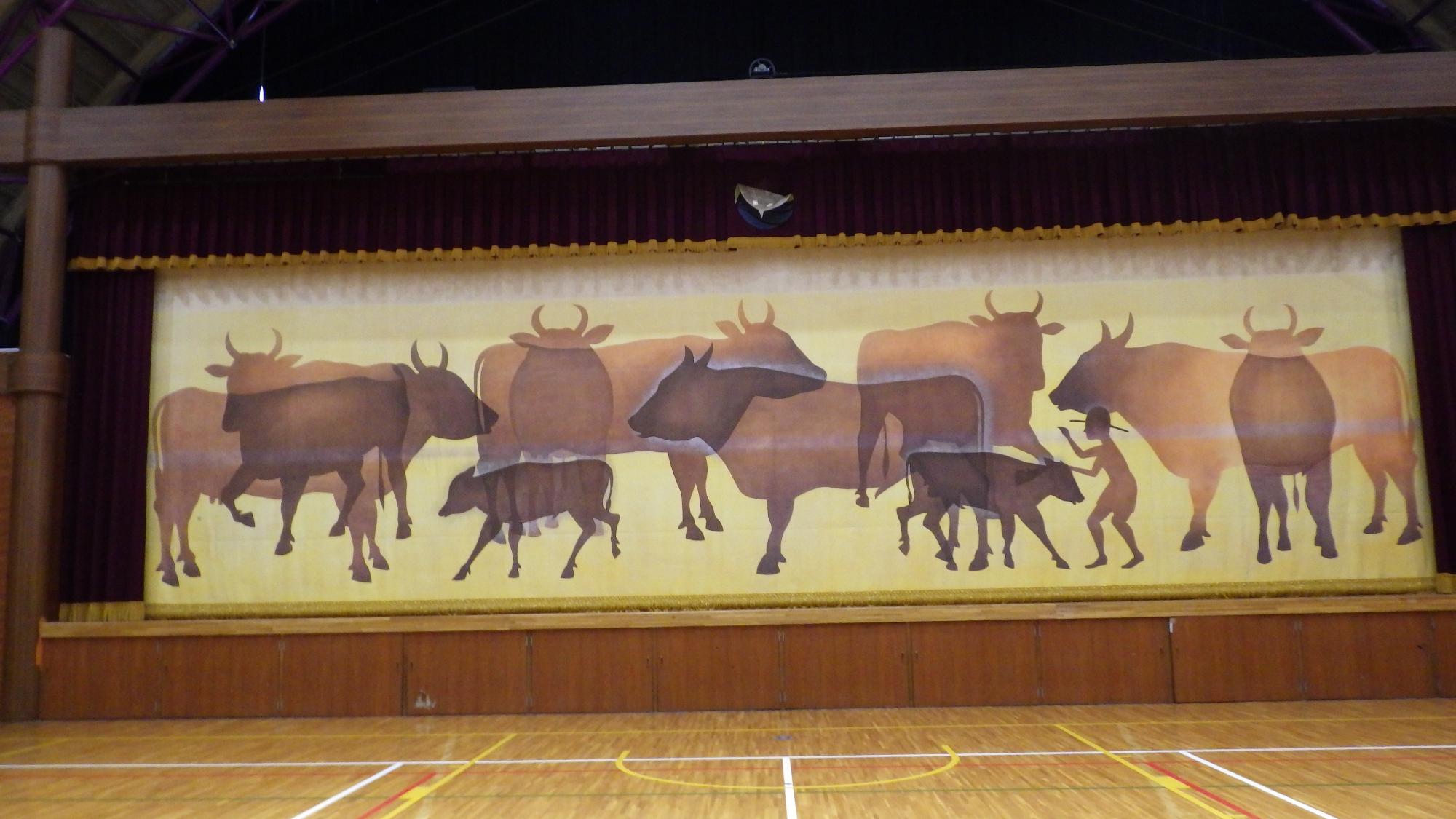 複数の牛のシルエットのイラストが描かれている体育館の舞台幕の写真
