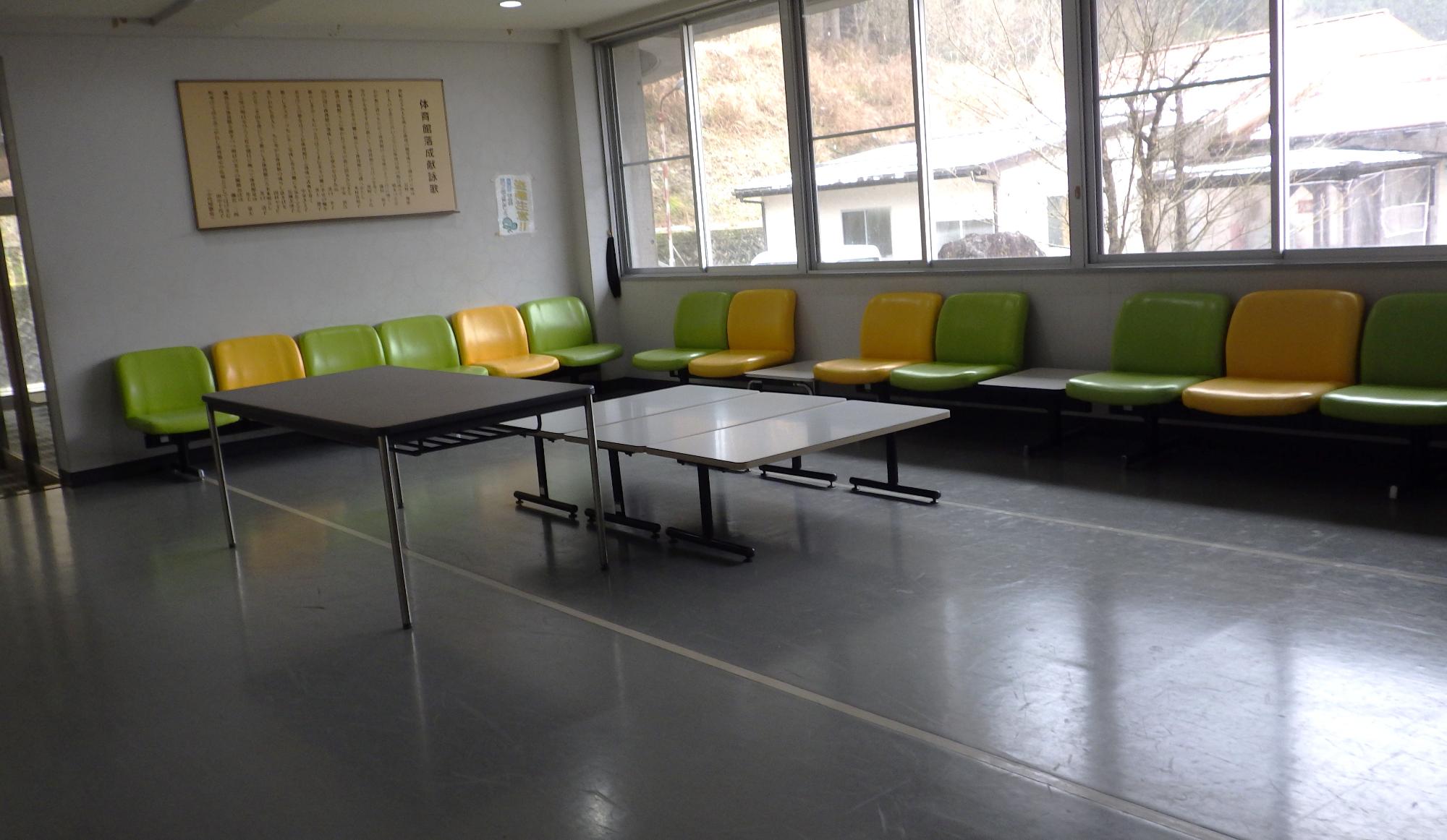 テーブルと壁沿いに椅子が複数設置された室内の写真