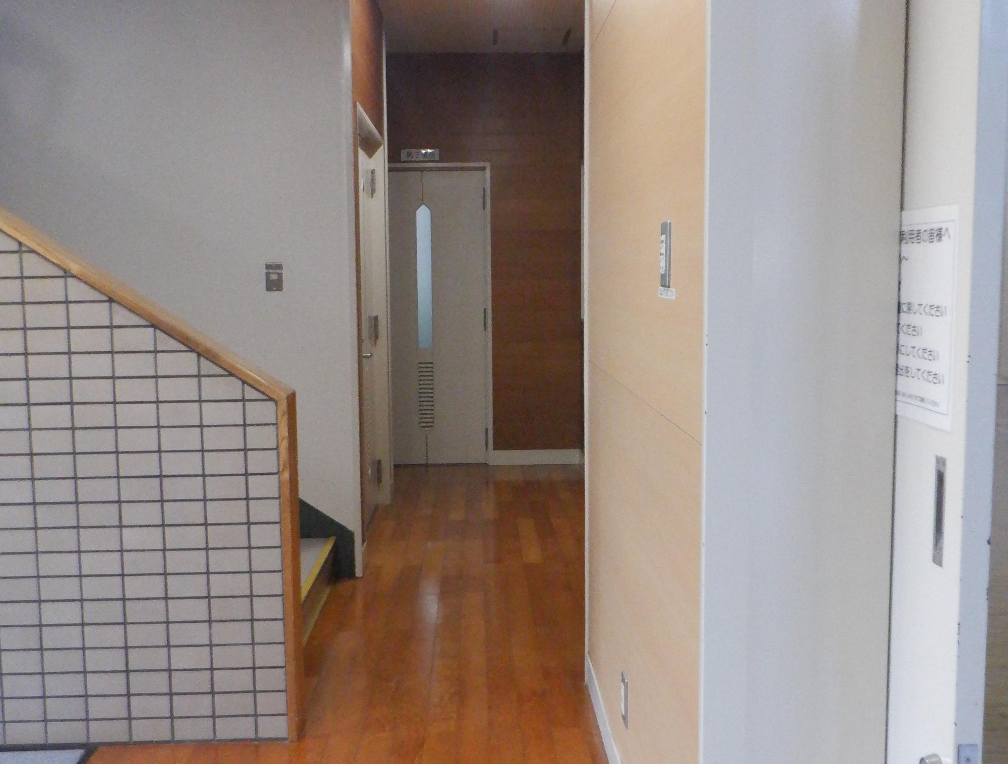 階段の奥に部屋へ続く扉がある建物内の写真