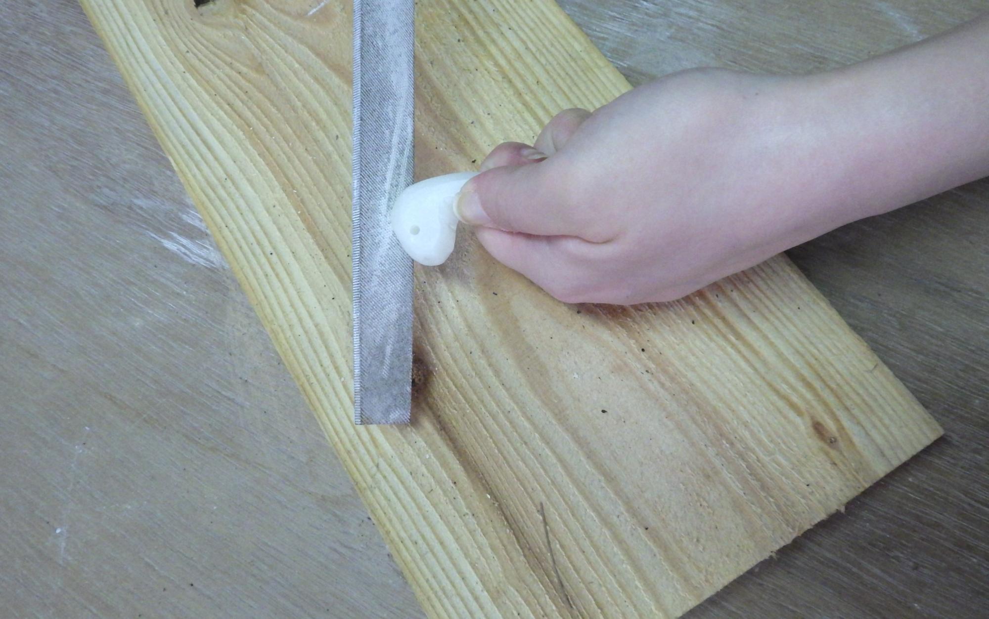 勾玉の形をした白い石をやする人の手元の写真