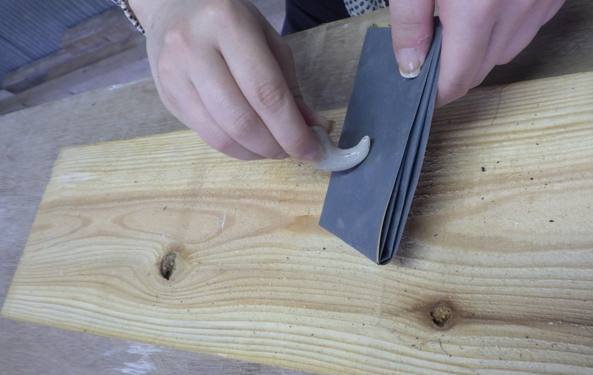 勾玉を紙やすりでやする人の手元の写真