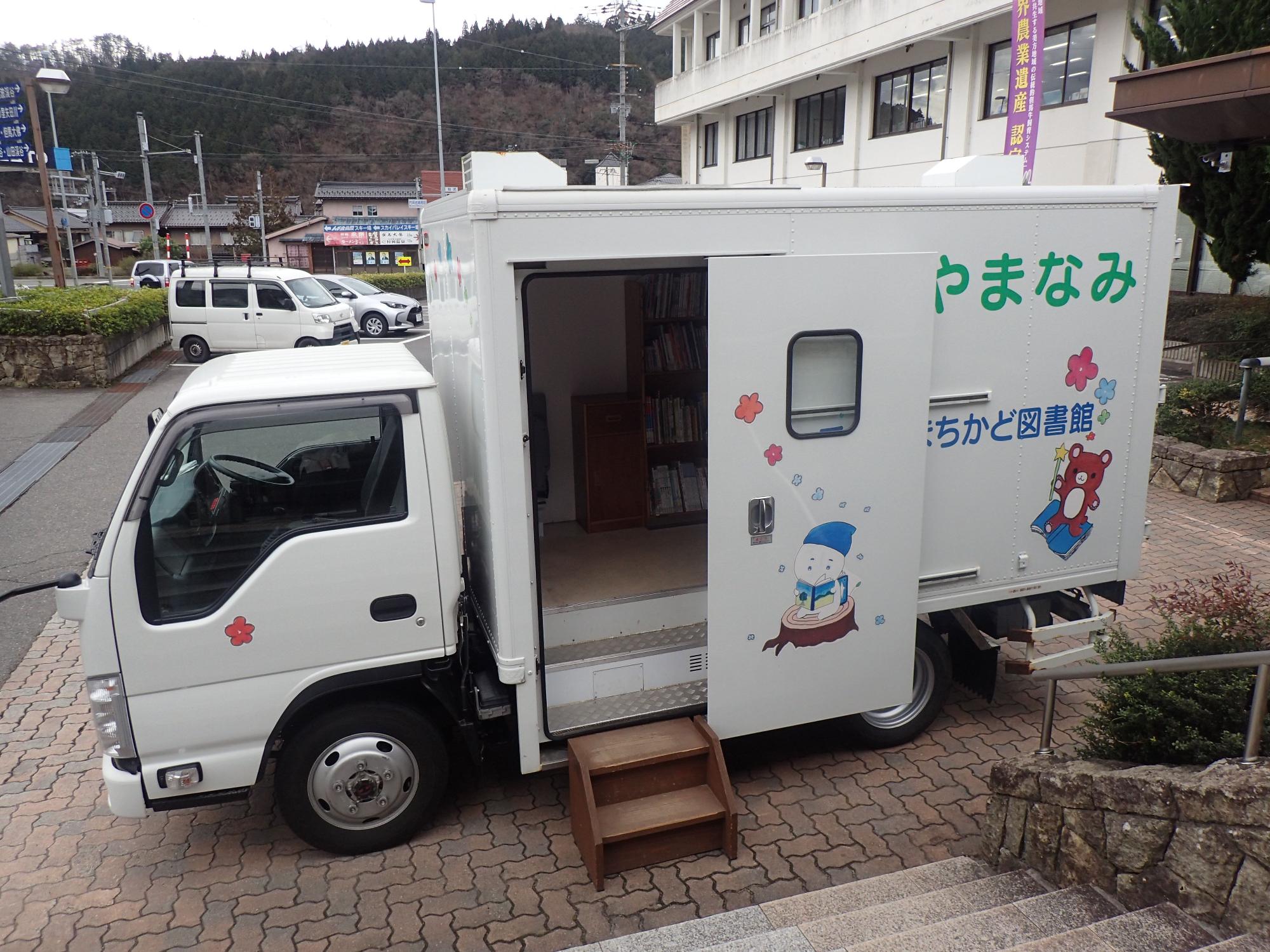 側面の扉が開いた荷台の中に本棚が設置されているトラックの写真