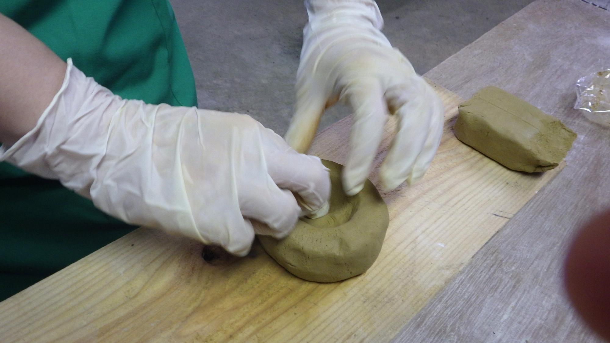 粘土の中心をくぼませている人の手元の写真