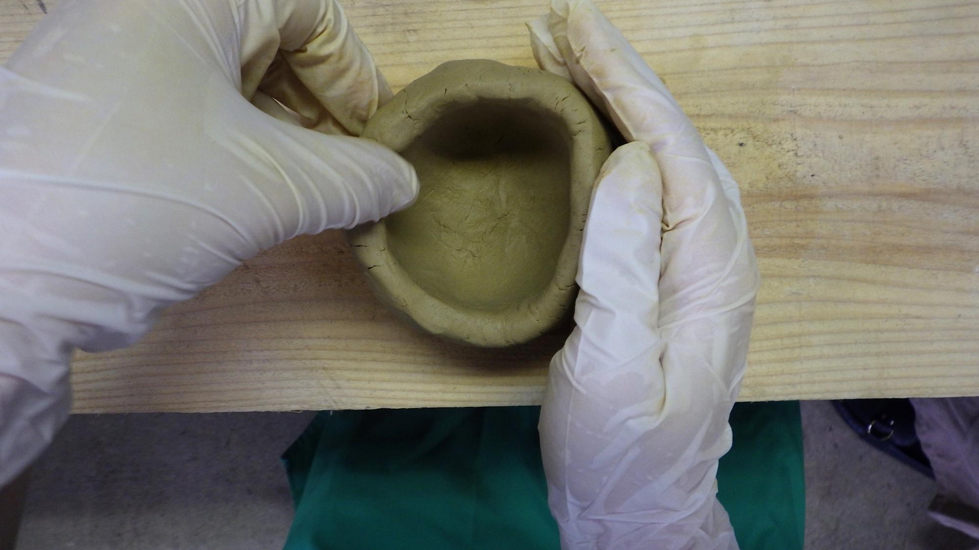 粘土を器の形に成形している人の手元の写真