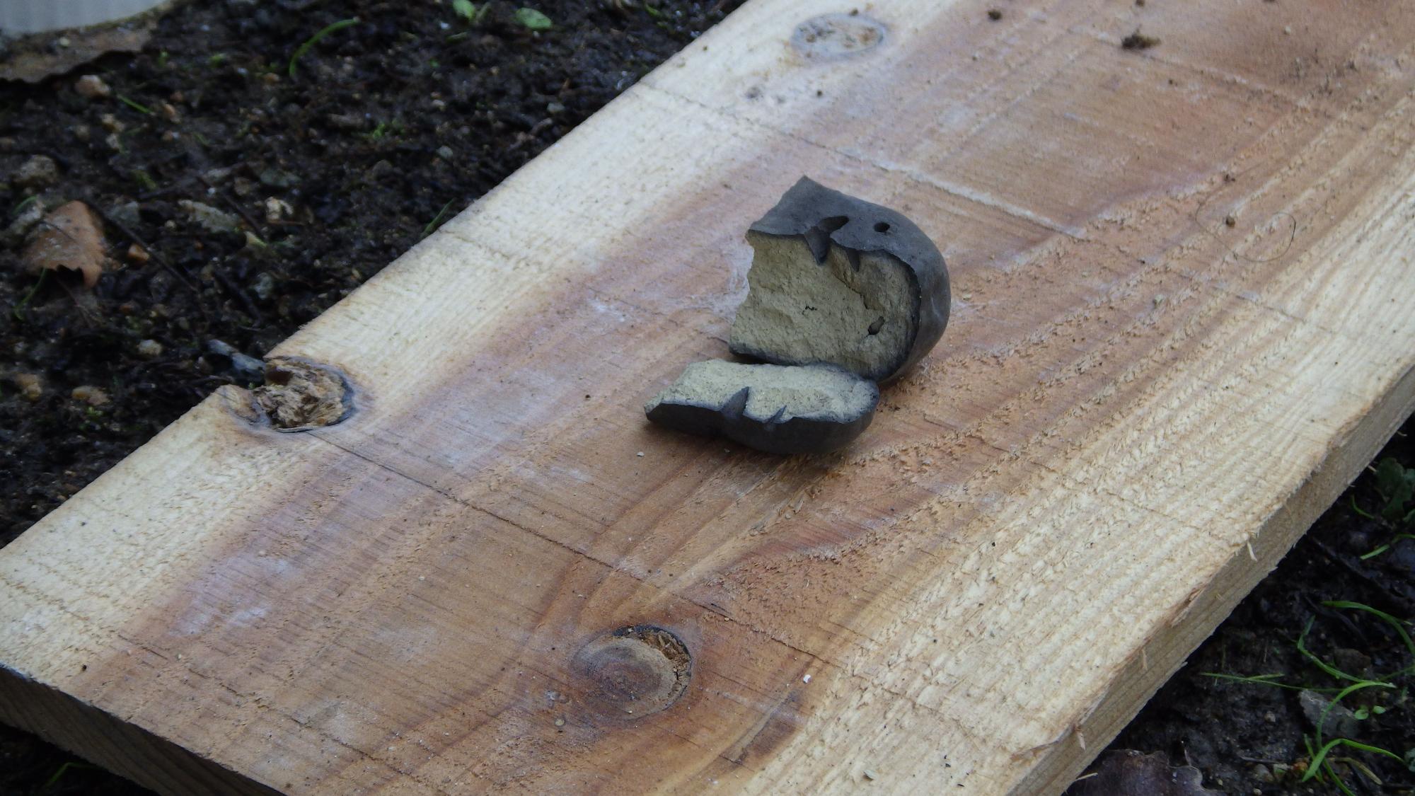 木の板の上に置かれた真っ黒に焦げた埴輪の頭の写真