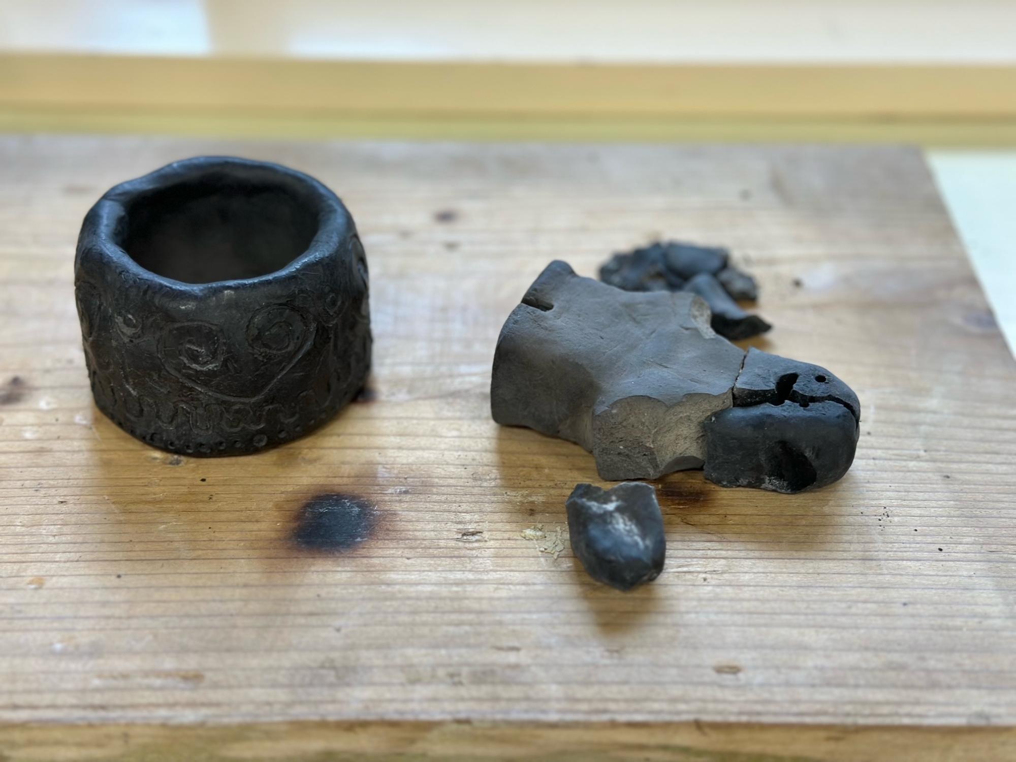 黒い器と割れた埴輪の写真