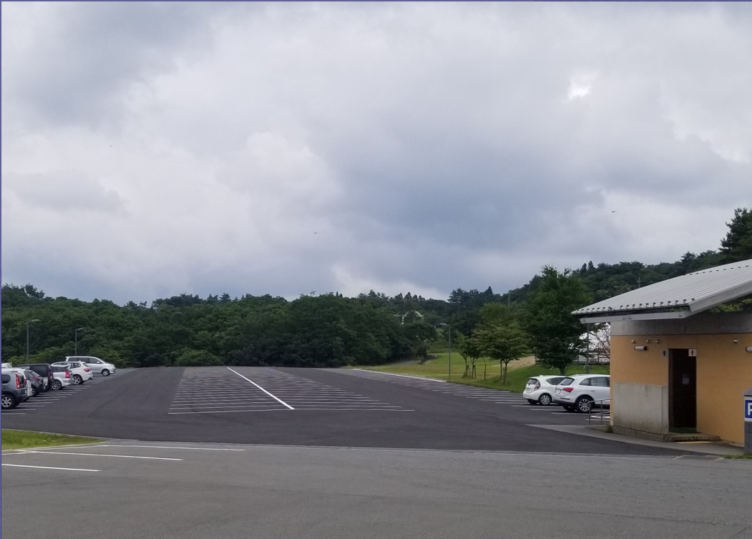 奥に森が見える駐車場の写真