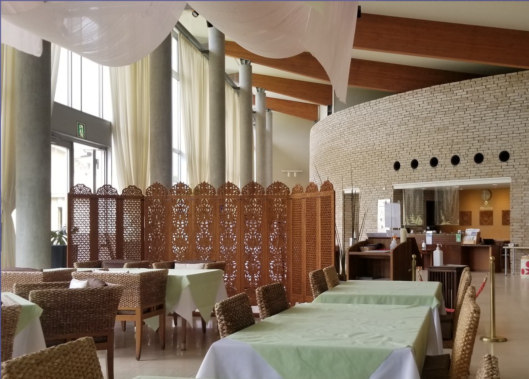 黄緑色のテーブルクロスがかけられたテーブルが並んでいるレストランの写真