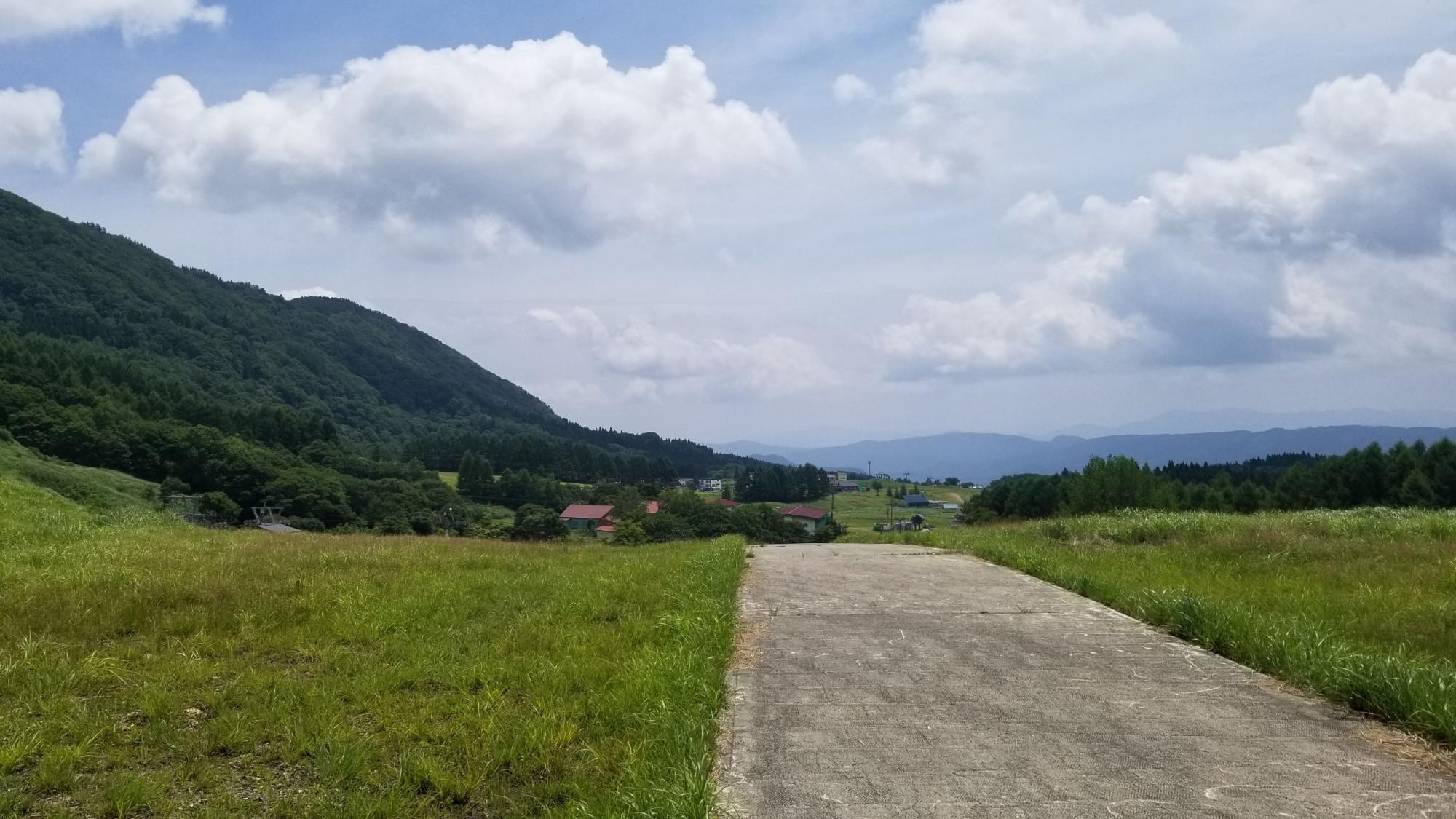 左奥に山の見える集落手前の道の写真