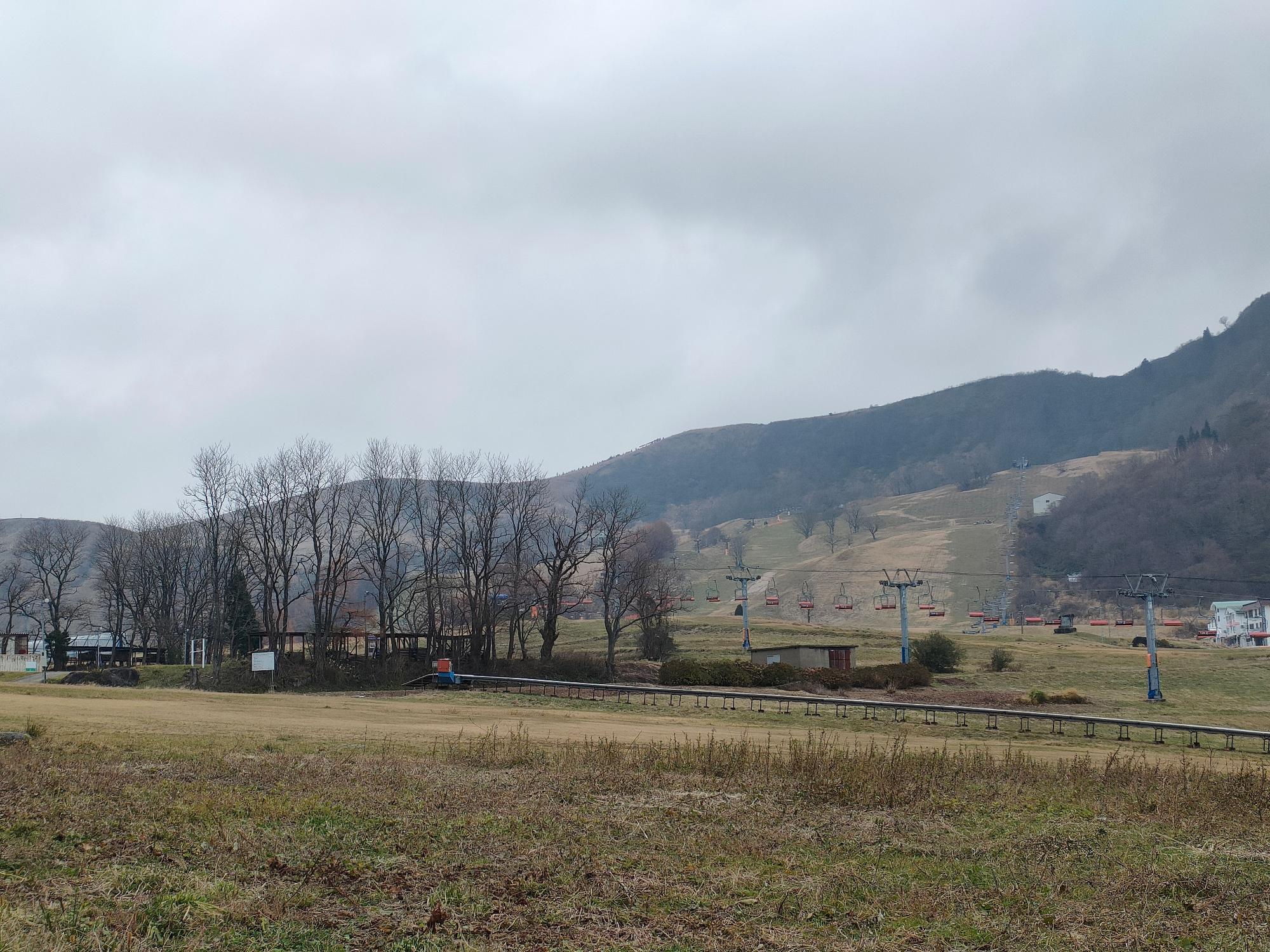 奥に山の見える草原に設置されたリフトの写真