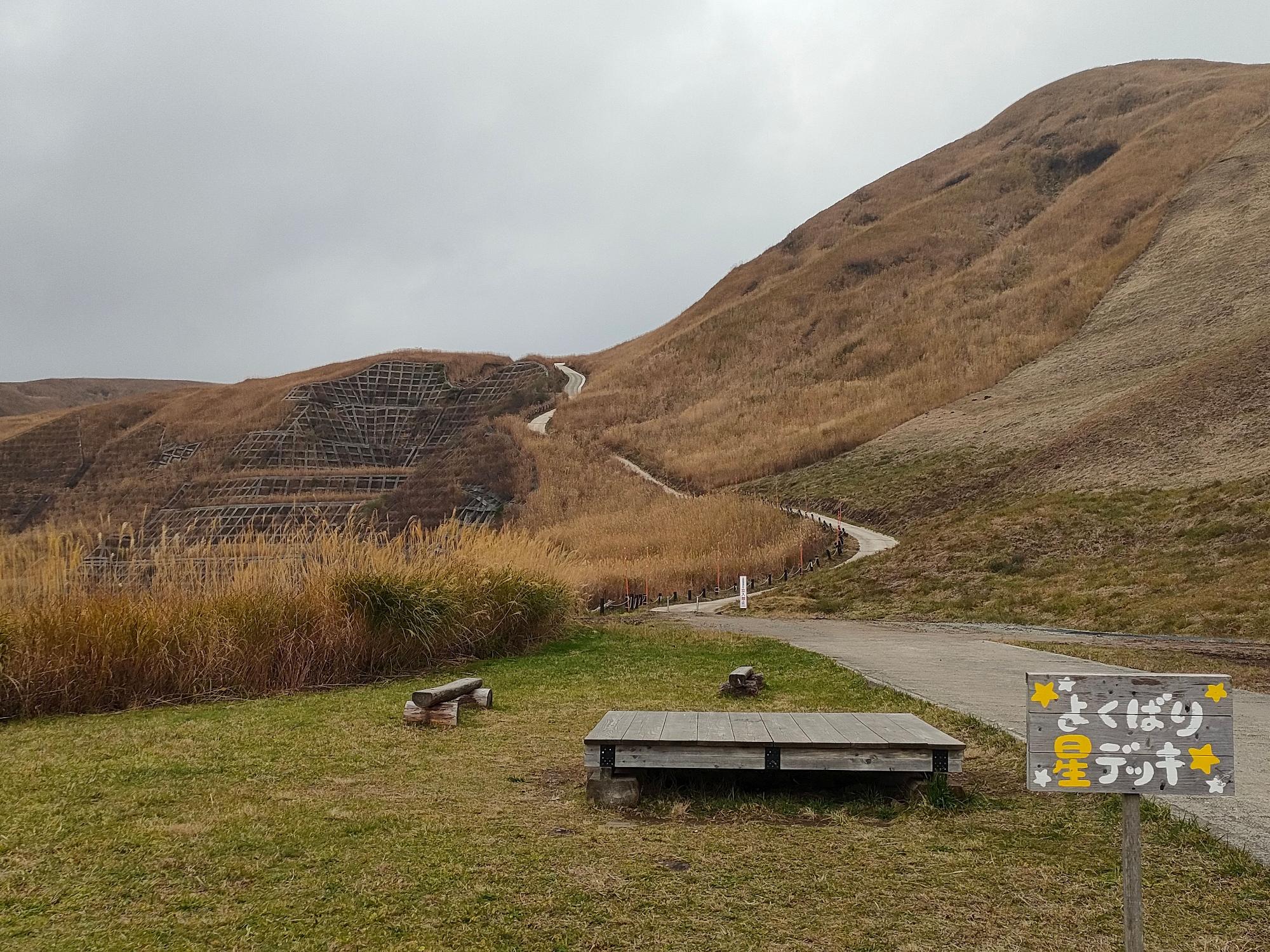 山の奥へと続く道の手前に置かれたデッキと「よくばり星デッキ」と書かれた看板の写真